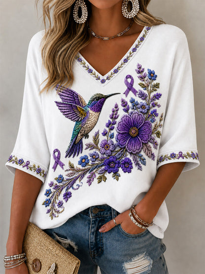 Camiseta feminina com decote em V, estampa floral roxa e beija-flor, de apoio à conscientização sobre a doença de Alzheimer